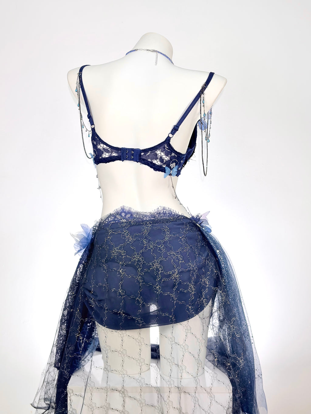 Back view of AVRY Delphine blue rave outfit with lace bra top and sheer draped skirt